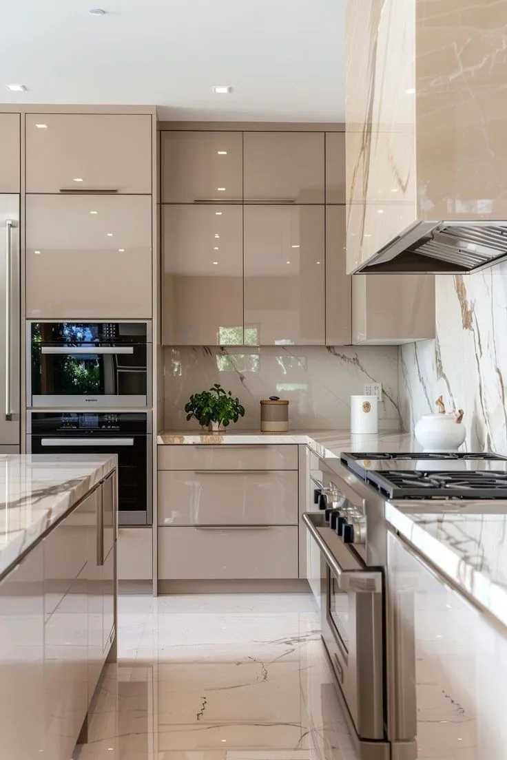 This kitchen glows with golden tones and polished marble. High cabinets and soft lighting create an airy feel. Natural wood flooring ties the elements together. A stunning choice for kitchen renovation ideas with a touch of luxury.