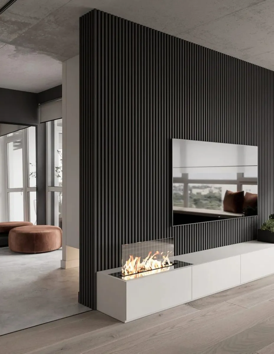 Dark Slatted Drama A striking black slatted wall creates a bold frame for the TV, complemented by a sleek white console and a contemporary fireplace. Ideal for adding depth and texture to minimalist interiors.