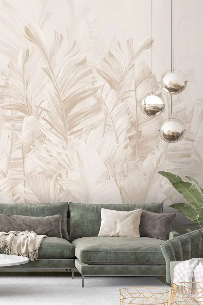 This wallpaper features delicate palm leaves in muted tones, blending seamlessly with the soft green velvet sofa. The metallic pendant lights add a touch of modernity, while the overall palette ensures a serene and inviting atmosphere. 