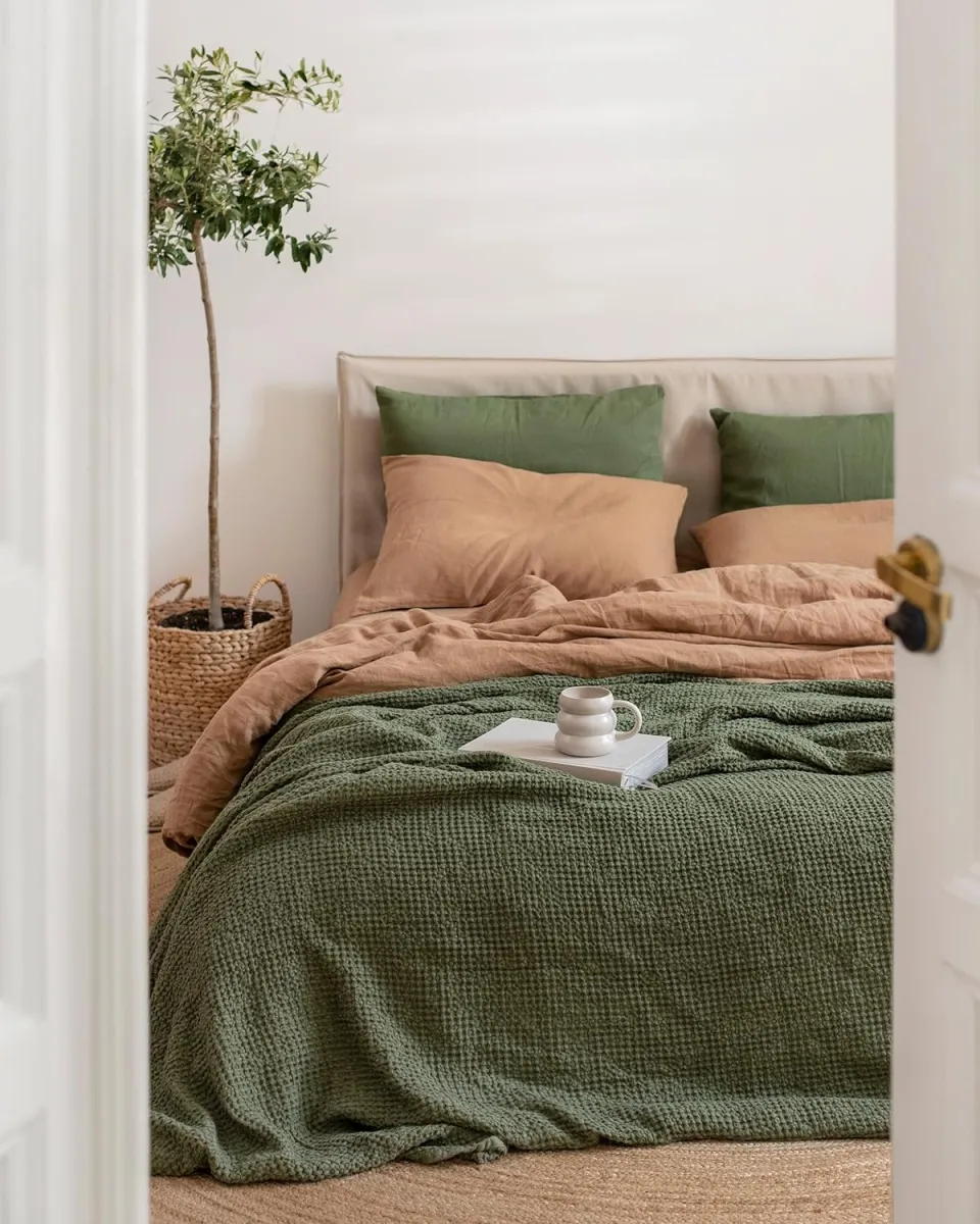 Green accents breathe life into this serene setup. The olive-green throw and matching pillows mirror the potted tree nearby, creating a sense of balance and connection to nature. A minimalist side table with a sleek ceramic mug adds elegance while maintaining simplicity. This look proves that with a thoughtful use of color and decor, you can create a refreshing retreat in any dorm room.