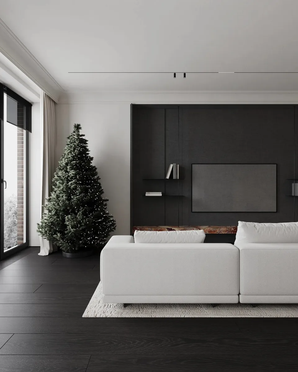 Cozy minimalist living room with dark wood floors and a festive Christmas tree. This living room is the perfect example of the minimalist apartment aesthetic. The modular off-white sofa sits atop a textured cream rug, softening the contrast against the dark wood floors. The built-in TV wall unit, covered in deep charcoal fabric, adds depth without clutter.