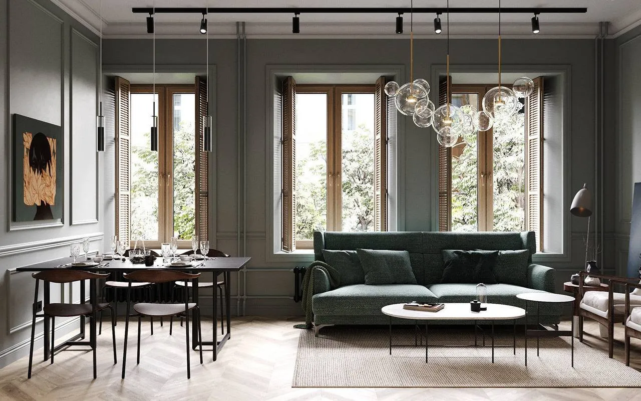 Luxury living room with soft sage-green walls, deep green minimalist sofa, natural wood window shutters, and warm parquet flooring, bathed in natural light.