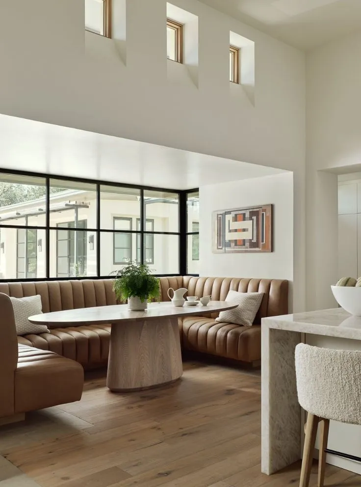 Cozy modern corner dining nook bathed in natural light, with built-in seating and simple, sophisticated decor for a stylish home.