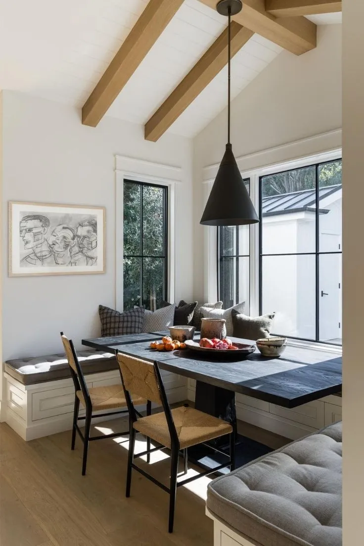 Warm and inviting corner dining nook with mustard-tone cushions, a rustic wooden table, and soft pendant lighting for a cozy feel.