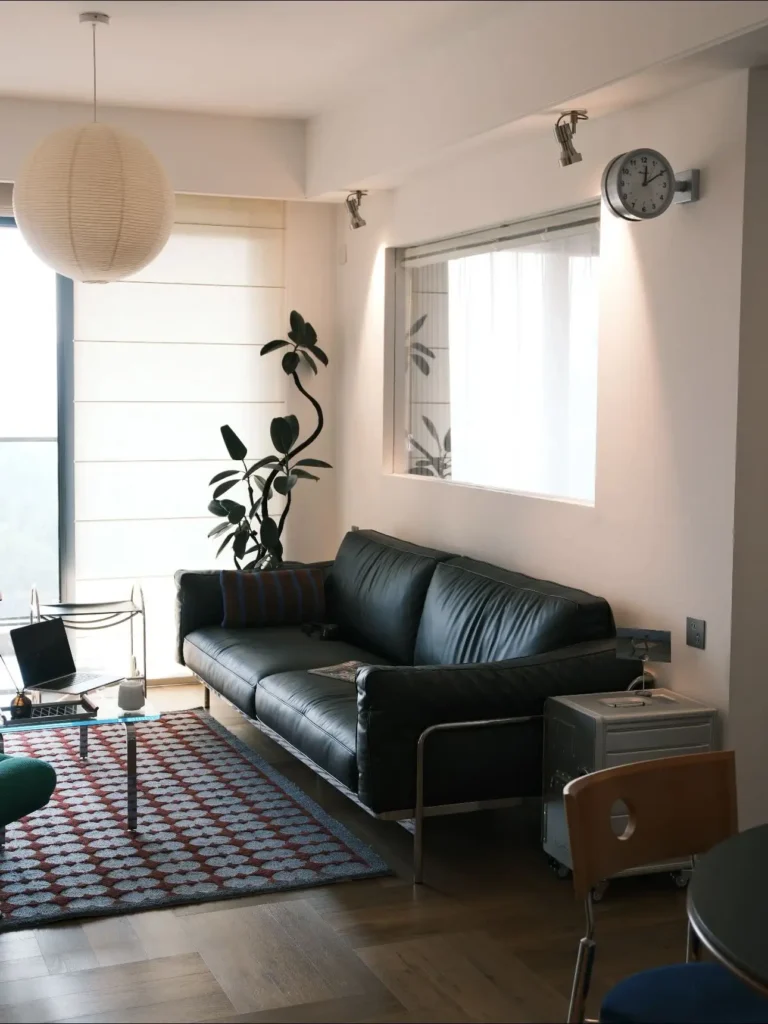 This sunlit living room shows how layered lighting and natural textures make a small apartment feel calm and welcoming. A mix of plants, warm wood floors, and graphic rugs adds depth without clutter. Save this cozy setup. #livingroominspiration #apartmentdecor #cozyinteriors #midcenturylivingroom #smallapartmentideas #interiorstyling #homeinspiration #designideas #modernlivingroom #cozyhome