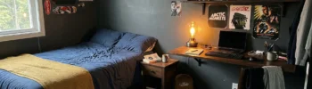 Dark bedroom ideas for teenage boys with charcoal walls, warm desk lamp light, and mustard accent throw.