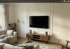 Picture Frame Molding Wall: The $100 Upgrade That Looks Like Custom Millwork Living room TV wall with picture frame molding painted white, showing three rectangular panels framing a mounted TV with a walnut console below.