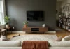 What Color to Paint Behind Your TV (The Choice That Changes Everything Else) Living room with deep charcoal paint behind mounted TV showing how dark wall color makes the screen blend in when off.