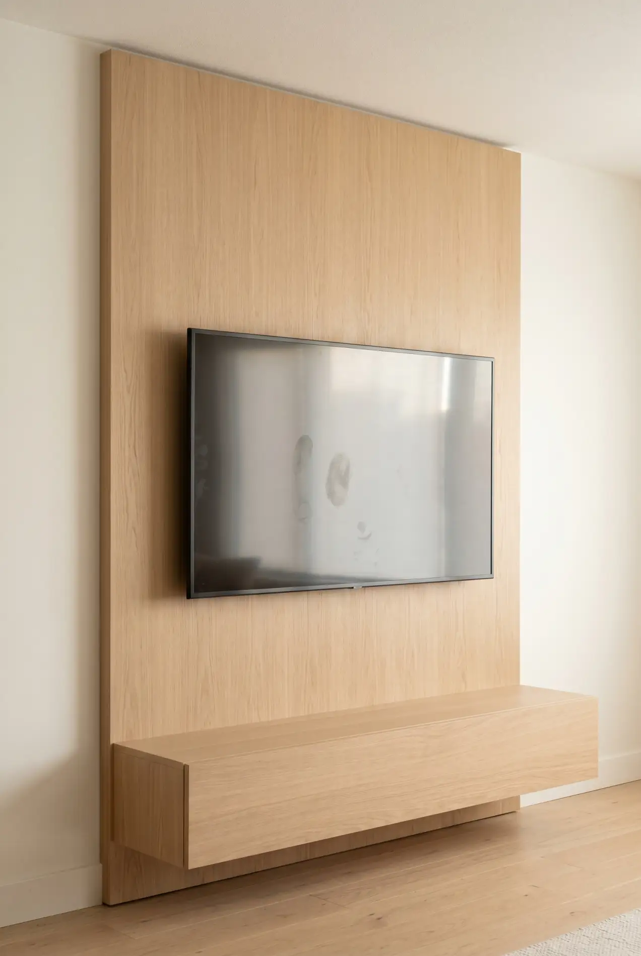 TV mounted on a horizontal white-oak wood panel with a matching low floating media unit below, warm white walls on each side.