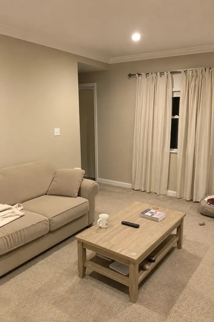 Wide shot of a beige living room nook with white trim and beige sofa before color drenching makeover.