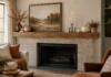 Fall Mantel Decor Without the Clutter: My Five-Object Layout Fall mantel with framed landscape art, cream pumpkins, amber vase, dried branches and flameless LED taper candles above an unlit fireplace.