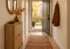 Small Fall Entryway Decor: Keep the Door and Walkway Clear Illustrative narrow rental apartment entryway with slim shoe cabinet, key bowl, fall branches, small pumpkin and flat rug while the front door remains open and the path clear.