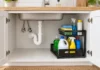 Under-Sink Organizers That Fit Around Pipes: Two Options to Measure First Illustration of a black L-shaped organizer beside accessible plumbing in a white sink cabinet