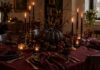 Halloween Looks Like a Dinner Party This Year Moody Halloween dinner table with plum candles and dark florals in a small apartment